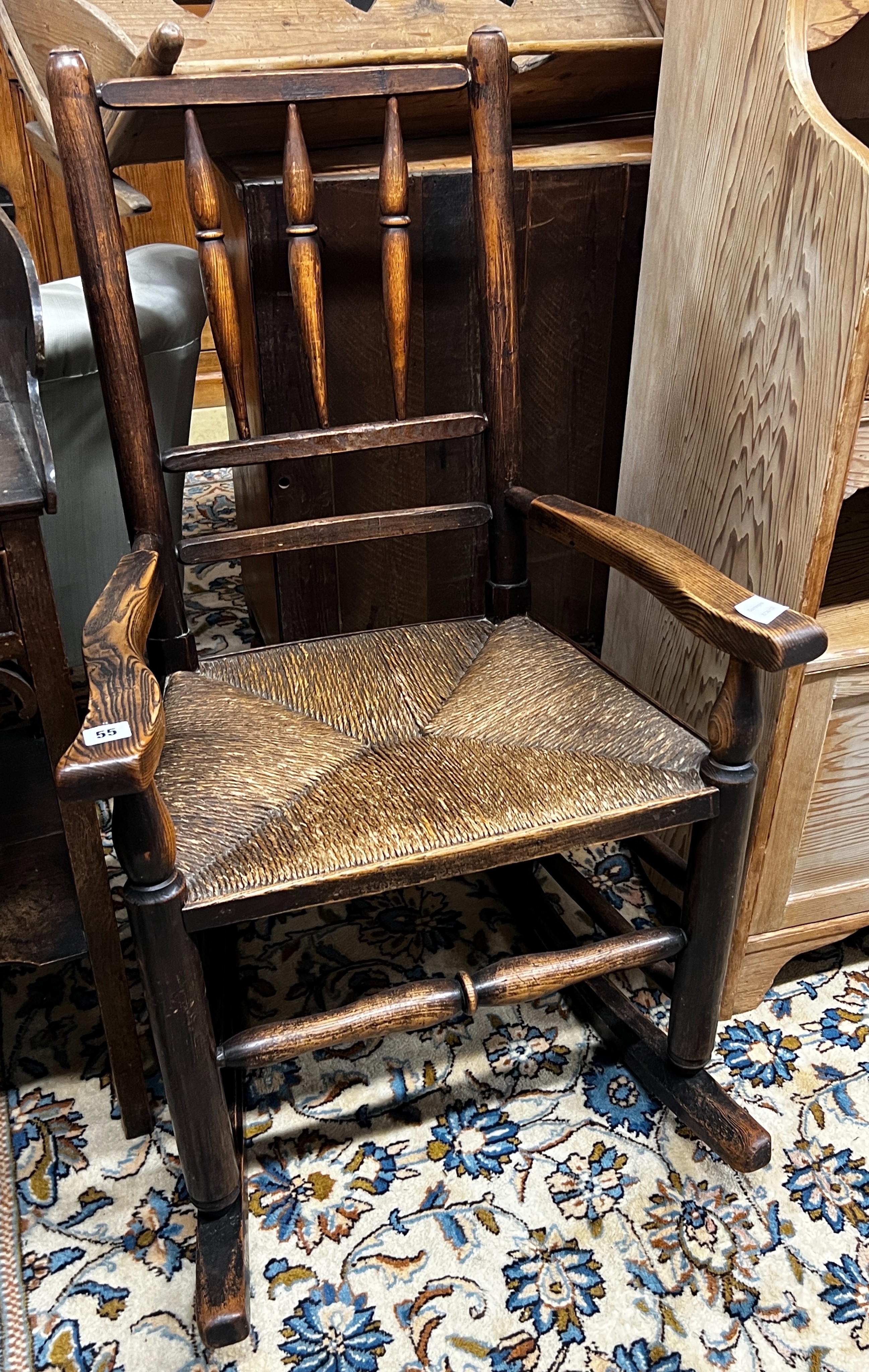 An early 19th century ash rush seat spindle back rocking chair, width 60cm, depth 46cm, height 94cm